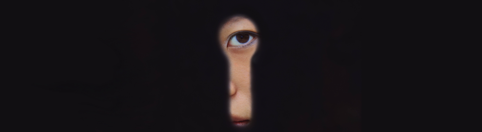 Eine chinesische Frau blickt in Schanghai durch ein Schlüsselloch