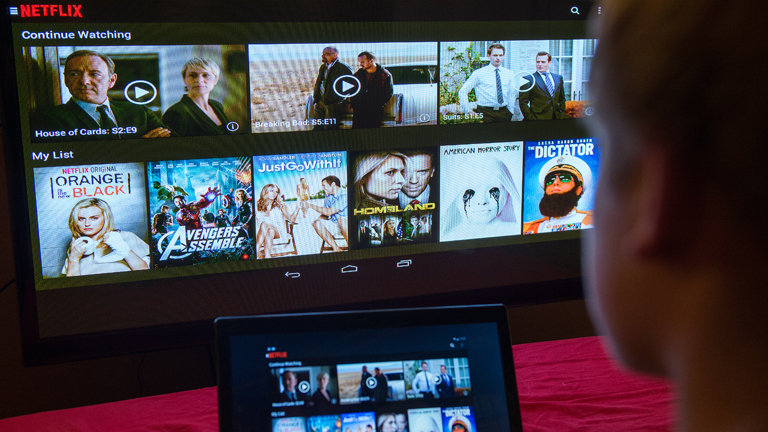 Ein junger Mann lässt sich eine Seite der Videostreaming-Firma Netflix am 14.09.2014 in Berlin von einem Laptop auf einem Fernsehbildschirm zeigen.