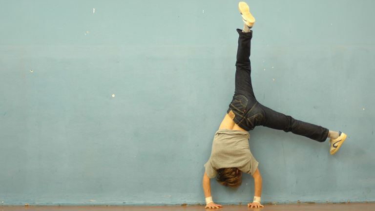 Ein Mann macht Breakdance an einer Wand.