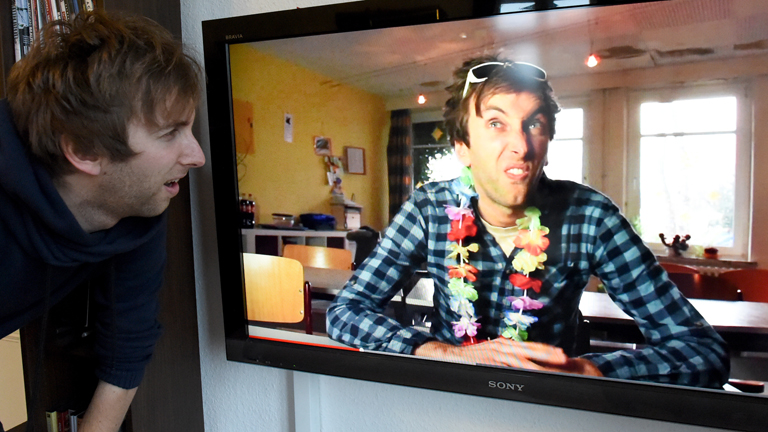 Torge Oelrich (Freshtorge) steht in seiner Wohnung in Wesselburen (Schleswig-Holstein) neben einem Fernseher, auf dem einer seiner Filme läuft.