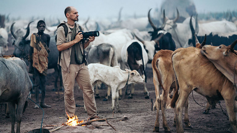 Fotograf Markus Mauthe im Südsudan neben Rindern