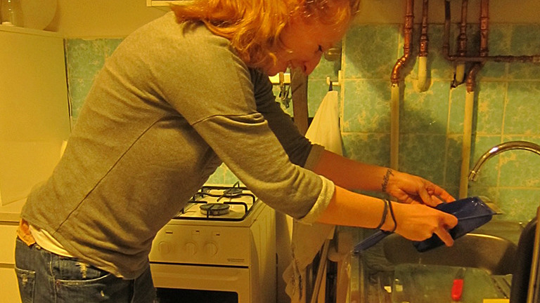 Eine Frau gießt Wasser über eine Kehrschaufel ab