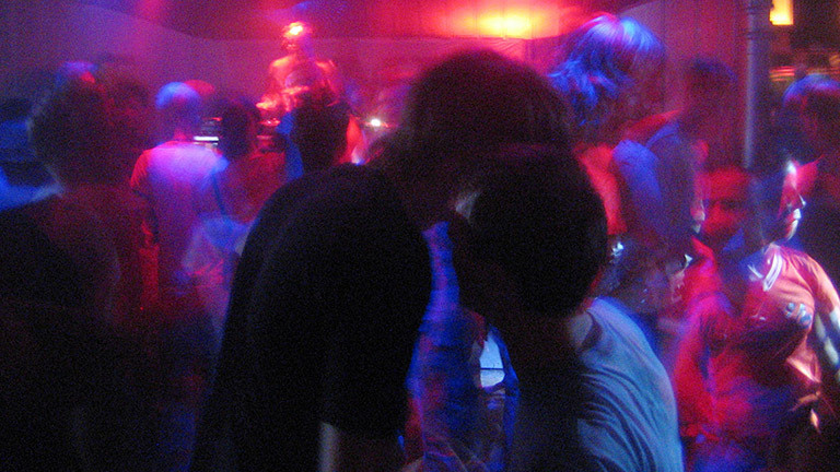 Ein Paar küsst sich auf der Tanzfläche in einem Club. 