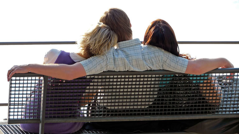 Ein Mann und zwei Frauen sitzen auf einer Bank