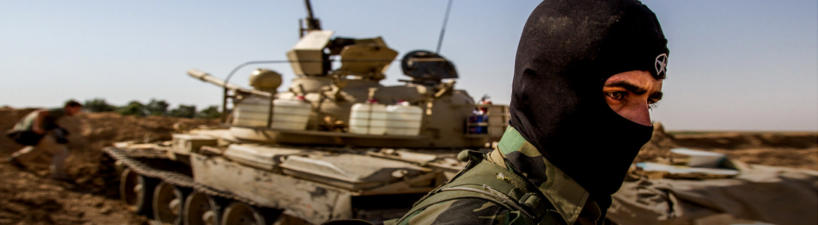 Ein kurdischer Soldat vor einem Panzer.