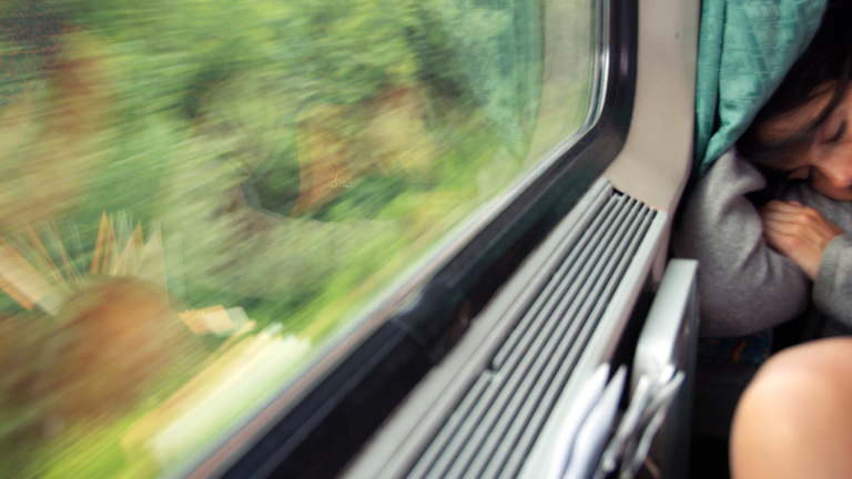 Eine Frau schläft in einer Bahn