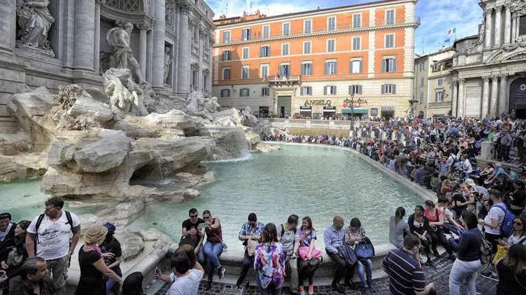 Touristen sitzen am Trevi-Brunnen in Rom.