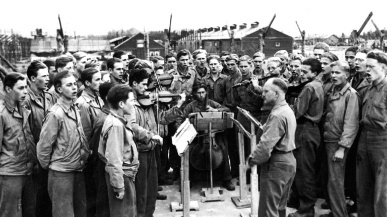 Eine Gruppe deutscher Kriegsgefangener in einem Lager der Amerikaner beim Singen.