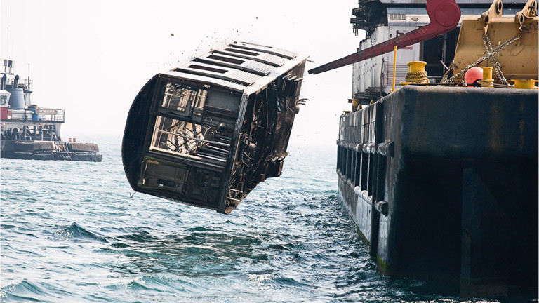 Ein Wagon wird von einem Boot ins Wasser entladen