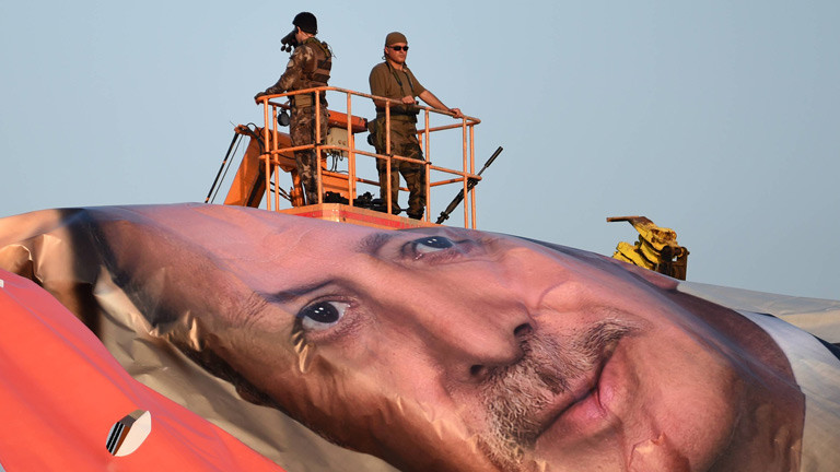 Ein aufgerolltes riesiges Banner von Präsident Erdogan, daneben Soldaten