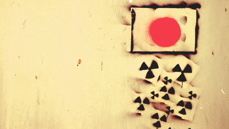 Die japanische Flagge an die Wand gesprüht, aus ihr heraus fallen kleine Atomsymbole.