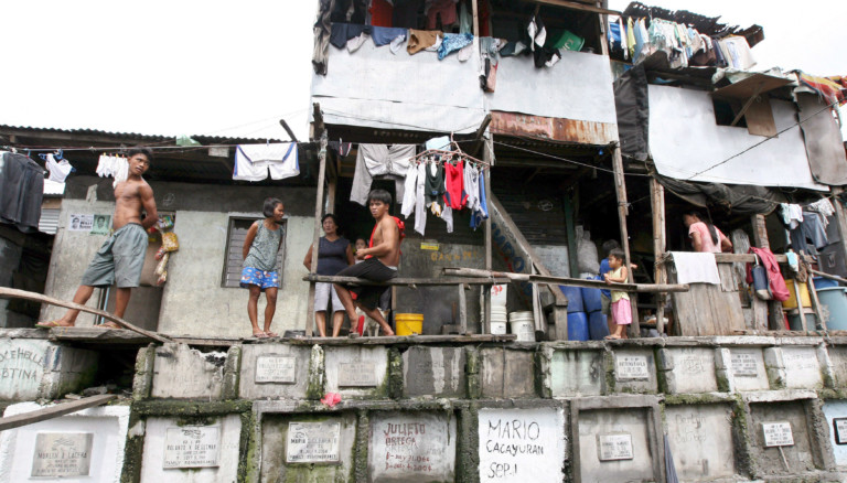Menschen und Hütten in Manila auf dem Friedhof.