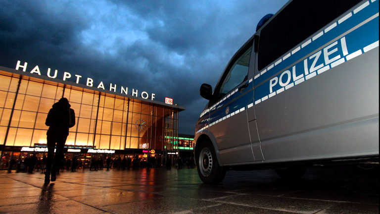 Eine junge Frau vor dem Kölner Hauptbahnhof, daneben ein Polizeiauto