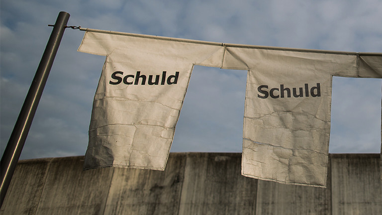 Ein Kunstwerk mit T-Shirts mit der Aufschrift "Schuld" ist am 14.10.2016 in Geldern (Nordrhein-Westfalen) vor dem Gefängnismauer der Justizvollzugsanstalt (JVA) Geldern zu sehen. Die JVA Geldern zählt zu den Hochzeitshochburgen unter den NRW-Gefängnissen. Foto: Maja Hitij/dpa (zu dpa Heirat hinter Gittern -Zwischen Sehnsucht, Sicherheit und Gefahr vom 04.11.2016)