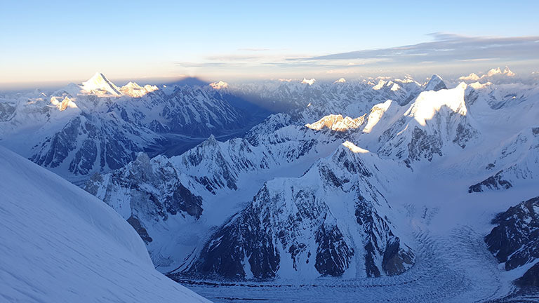 Schatten des Broad Peak fällt auf Berge des Karakorums