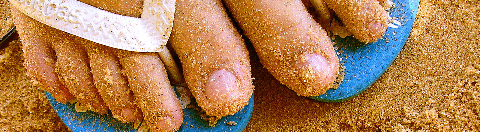 Barfuß in Flipflops auf Sand
