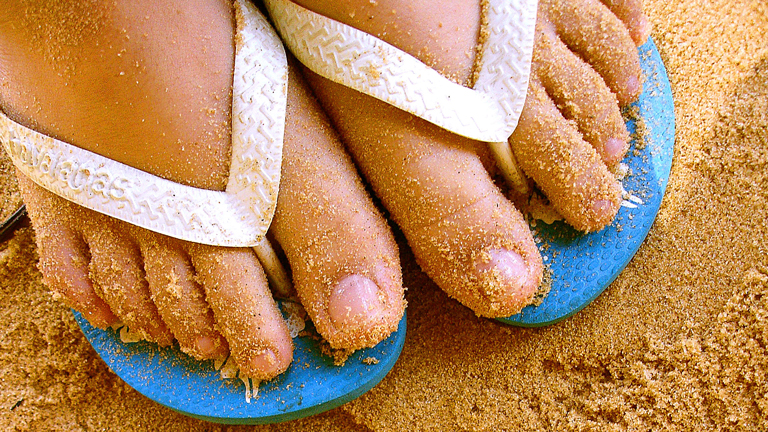Barfuß in Flipflops auf Sand