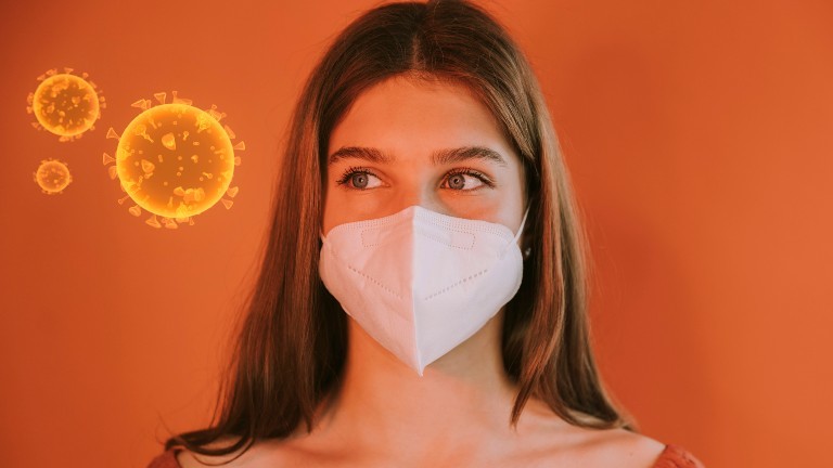 Eine Jugendliche trägt eine FFP2-Maske und schaut auf eine Grafik des Coronavirus.