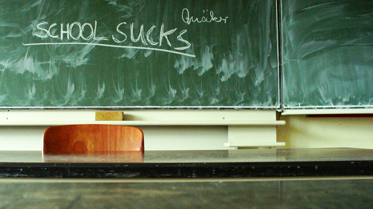 Schultafel, auf der "School sucks" steht.