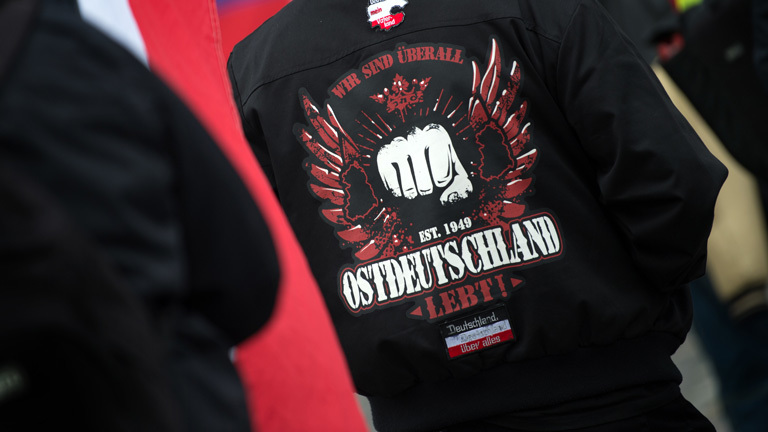 Ein Teilnehmer einer Pro-Le-Pen Demonstration der Thügida vor der Frauenkirche in Dresden (Sachsen) trägt am 06.05.2017 eine Jacke mit den Aufdrucken «Deutschland mein Vaterland, Est. 1949 Ostdeutschland lebt und Deutschland über alles».