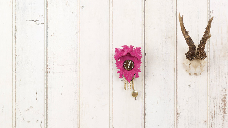 Geweih und Kuckucksuhr hängen an einer Wand.