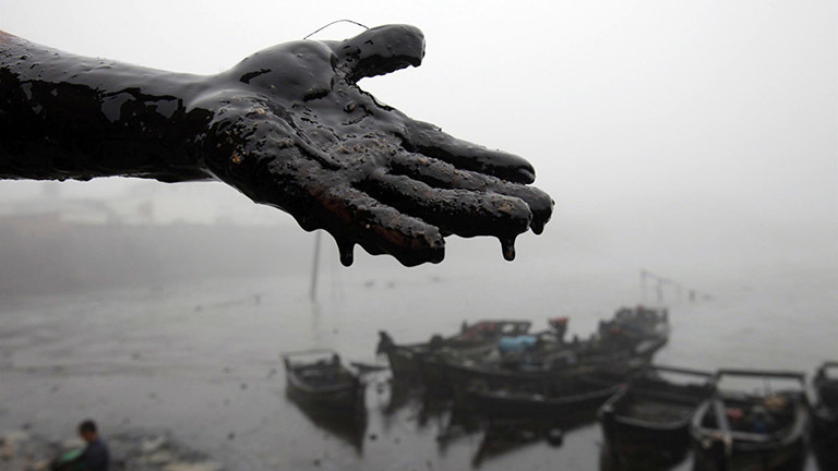 Ein Mann hat schwarzes Öl an seiner Hand.