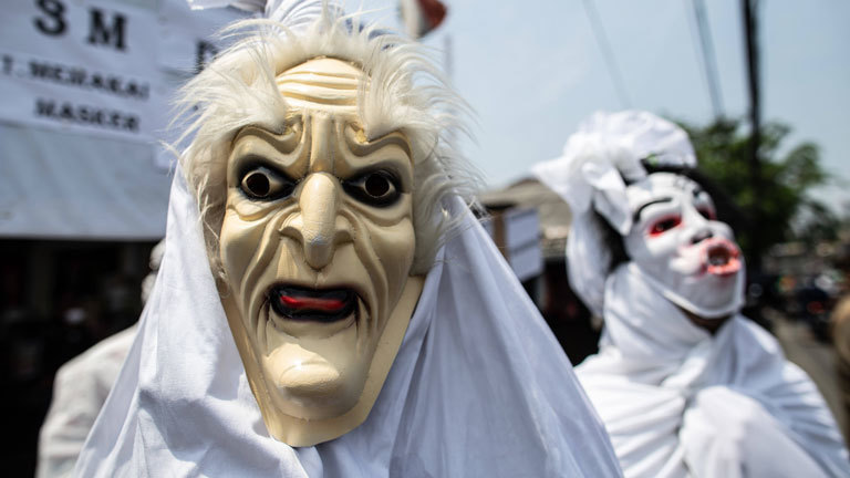 Menschen, die mit weißen Tüchern und Masken als indonesische Pecong-Geister verkleidet sind.