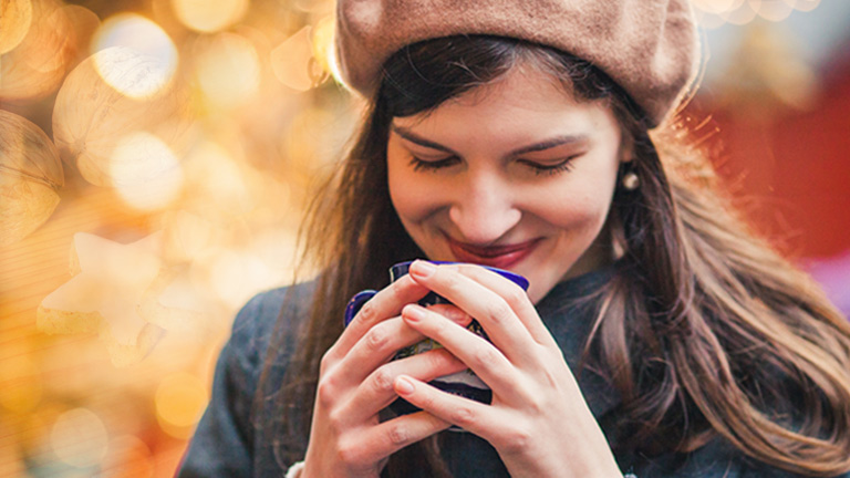 Eine Frau schnuppert an der Glühweintasse