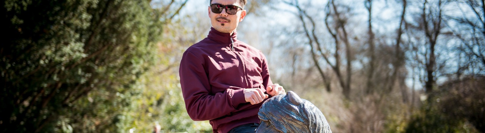 Ein Mann sitzt auf einem zu kleinen Bronzepony.