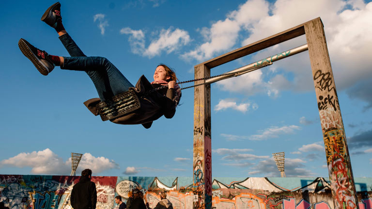 Eine glücklich wirkende Frau auf einer Schaukel.