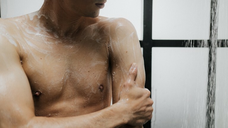 Ein Mann steht unter der Dusche und seift sich ein.