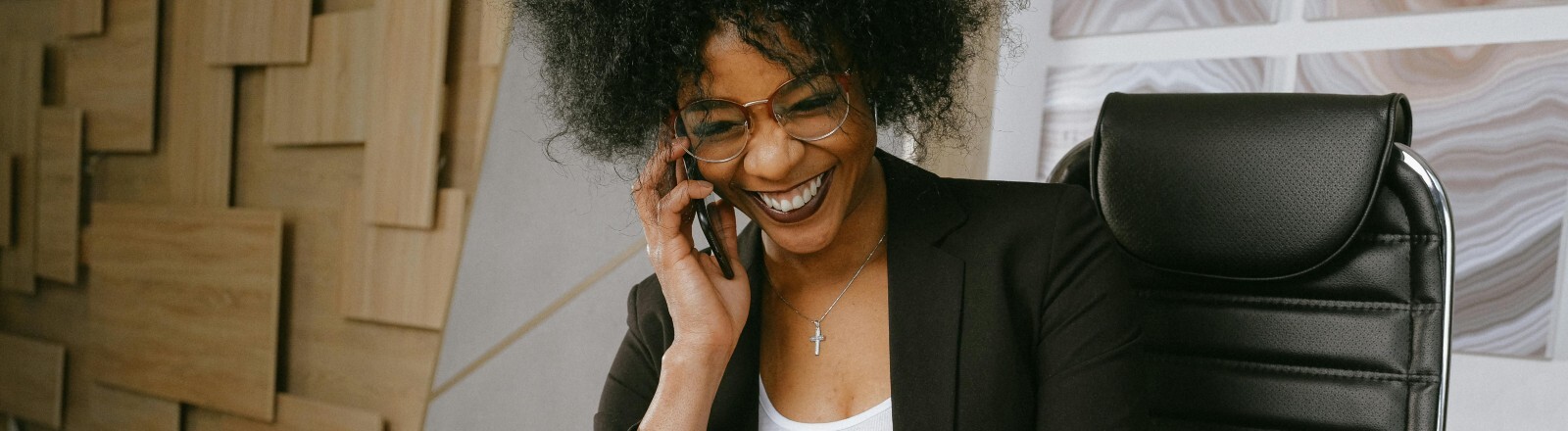 Eine Frau telefoniert und lacht dabei.