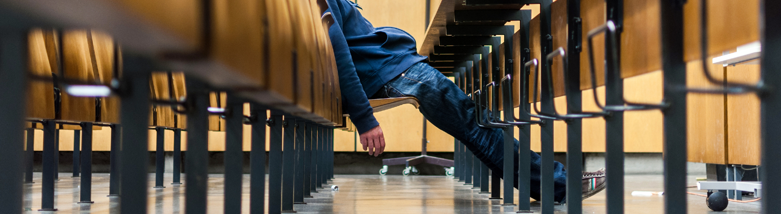 Ein Mann sitzt schlapp in einem Hörsaal.