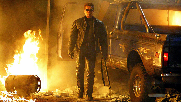 Der Terminator (Arnold Schwarzenegger) steht im Kinofilm "Terminator 3 - Rebellion der Maschinen" neben einem Autowrack.