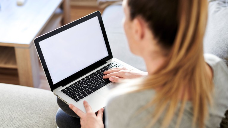 Eine Frau sitzt zu Hause an ihrem Laptop.