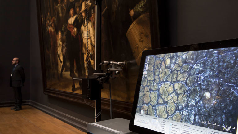 Ein Monitor zeigt ein Mikroskop-Bild auf dem ein 4x6-Millimeter großer Ausschnitt von Rembrandts "Nachtwache" zu sehen ist.
