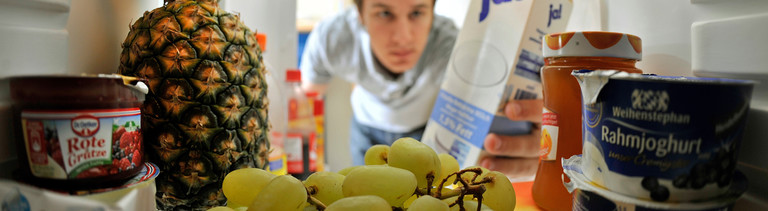 Ein Mann schaut in seinen Kühlschrank, vollgestopft mit Joghurt, Früchten, Milch, Marmeladen. Bild: dpa