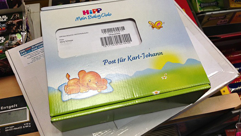 Ein Paket von Hipp liegt auf einem weiteren Paket, "Post für Karl-Johann" steht darauf.