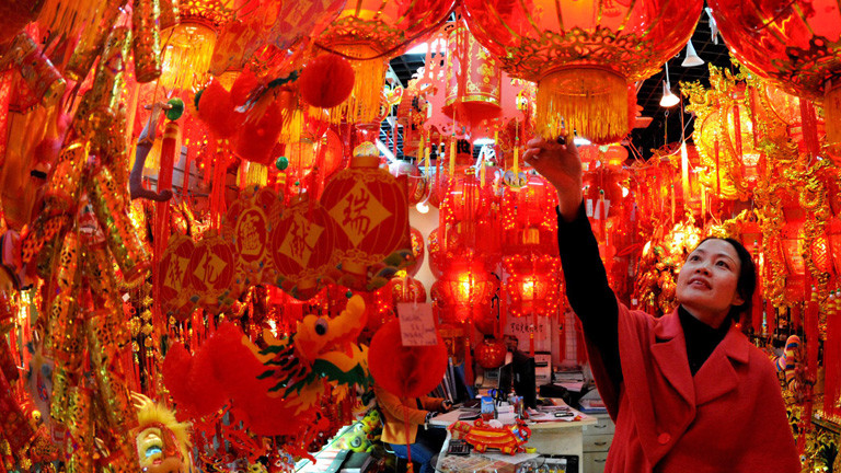 Eine Chinesin steht in einem Raum voller roter Lampions. Alles Deko für das Neujahrsfest in China; Bild: dpa