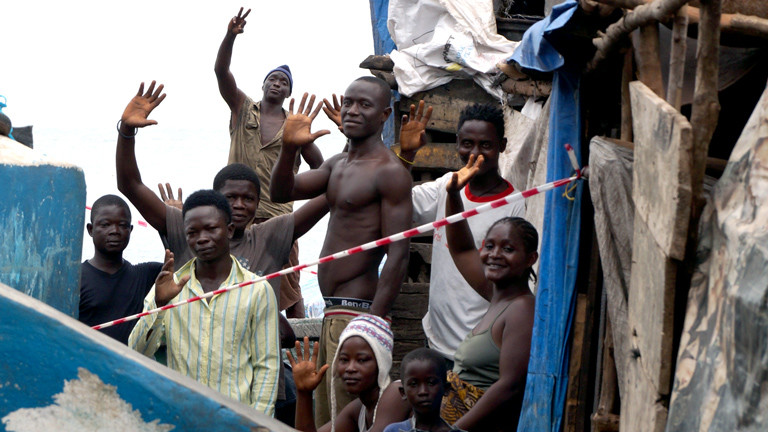 In einem Slum in Freetown wird eine Gasse mit einem Band abgesperrt. Die Menschen stehen unter Quarantäne.