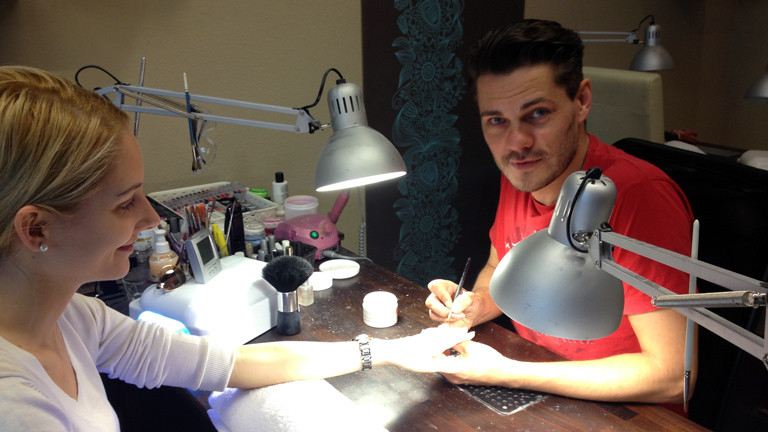 Der Nageldesigner Alex Schneider in seinem Studio mit einer Kundin