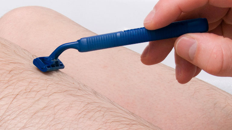 Männerbeine und ein blauer Rasierer