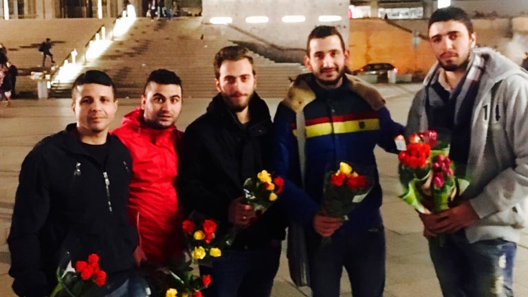 Syrische Flüchtlinge verteilen Rosen am Kölner Hauptbahnhof