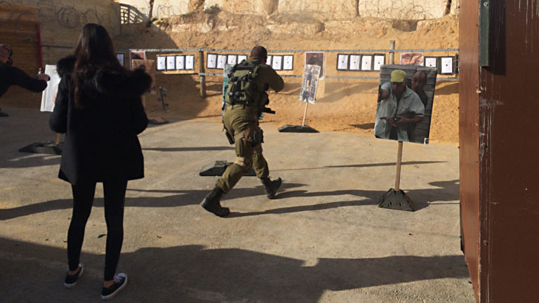 Touristen in Israel stehen vor einer Mauer an der Zielscheiben hängen
