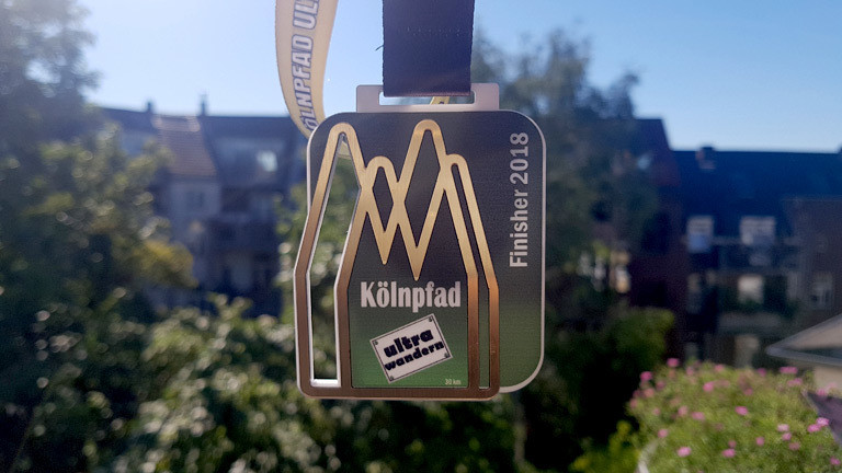 Reporterin Caro Köhler erhält eine Medaille nach einer vollbrachten Ultrawanderung.