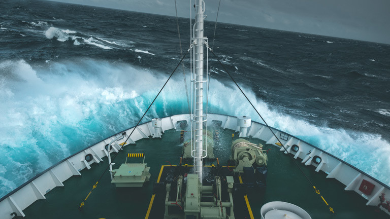 Ein Schiff fährt durch hohe Wellen.