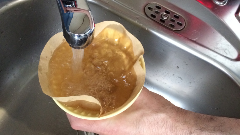 Ein Kaffeefilter wird mit Wasser gereinigt.