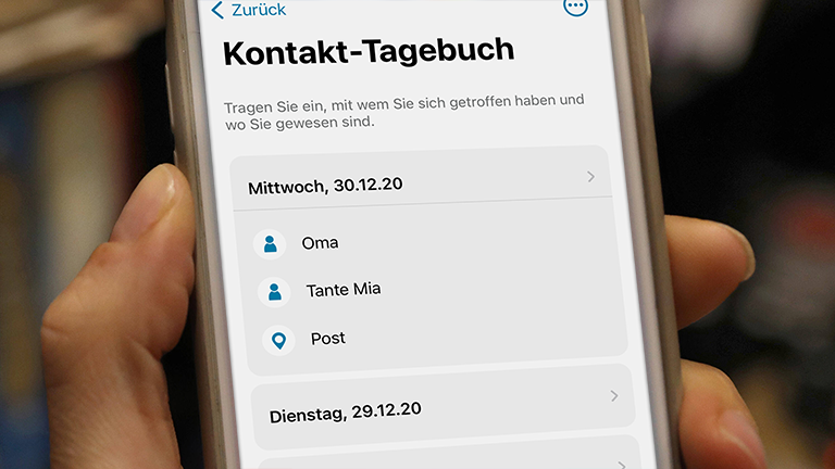 Eine Hand hält ein Handy, auf dem das Kontakt-Tagebuch der Corona-Warn-App geöffnet ist.