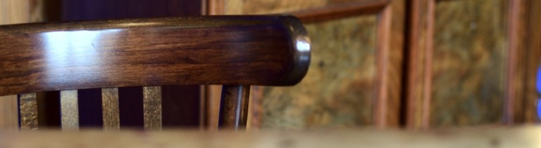 Ein leerer Holzstuhl an einem Tisch.