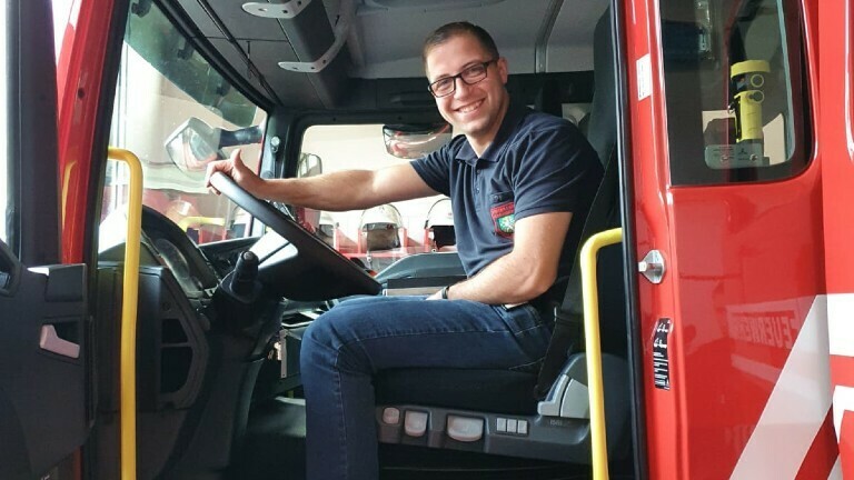 Feuerwehrmann Sascha sitzt in seinem Einsatzwagen.